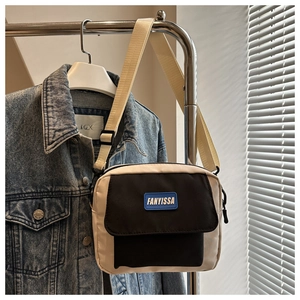 Detail showing beige canvas small square bag with black pocket and adjustable strap