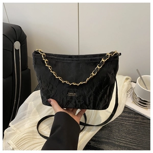 Detail shot of the black pleated texture shoulder bag with gold chain and logo patch