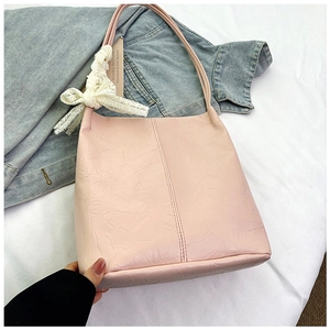 Close-up of pleated texture on light pink bucket bag with a delicate lace bow detail