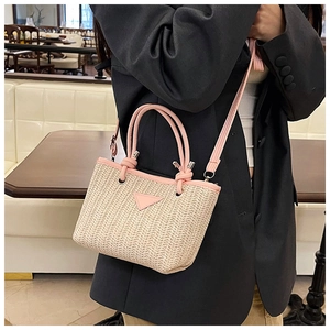 Detailed shot of a woven straw bucket bag featuring pink synthetic leather trim and handles