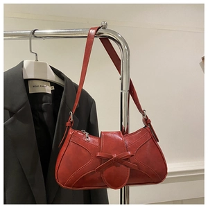 Détail du sac à épaule rouge avec nœud papillon en cuir brillant sur un cintre