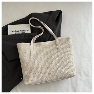 Gros plan sur la texture du sac cabas en paille tressée et lanières en cuir