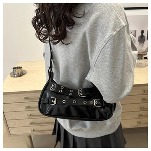 Vue de dos d'un sac à bandoulière punk Y2K noir avec œillets argentés porté par un mannequin