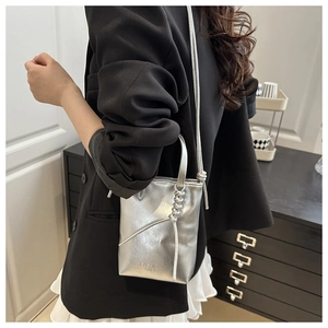 Détail du sac seau argenté métallisé avec bandoulière nouée et texte de mode chic