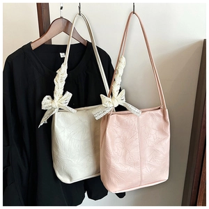 Detail of pleated PU leather tote bags featuring delicate white lace bow accents