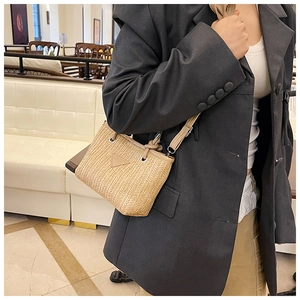 Close-up of a beige woven straw bag with leather patch detail on a cafe background