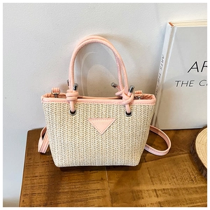 Close-up of pink leather trim and fashion label on a woven straw bucket bag
