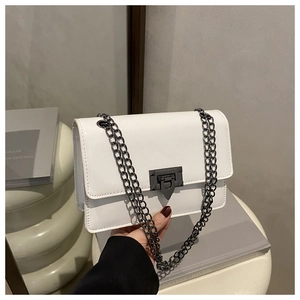 Détail d'un sac à bandoulière en cuir blanc avec finitions en métal noir et chaîne