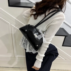 Glossy black crescent shoulder bag with lace bow decoration and silver studs