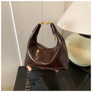 Detailed close-up of dark brown patent leather dumpling bag with golden metal hardware