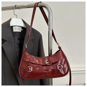 Détail du sac baguette en similicuir rouge foncé avec boucles et œillets argentés