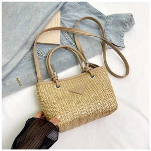 Detailed close-up of woven straw tote bag featuring herringbone texture and fashion leather patch