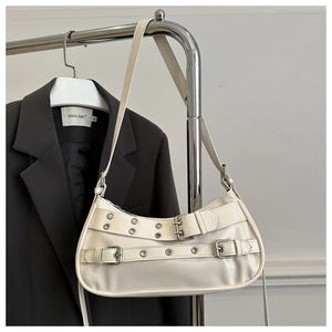 Détail du sac baguette crème en similicuir avec œillets argentés et boucles de ceinture