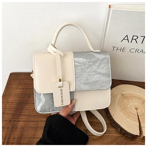 Detail of color-block mini handbag with silver pleated texture and fashion tag on wood