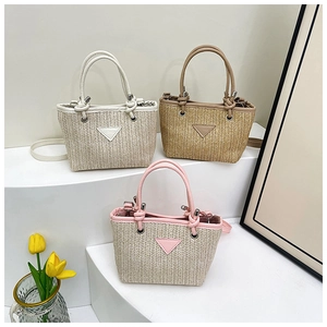 Detail of woven straw tote bags in beige and pink with leather trim on display