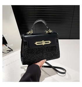 Detail of black trapezoid handbag with shimmering glitter finish and gold twist lock clasp