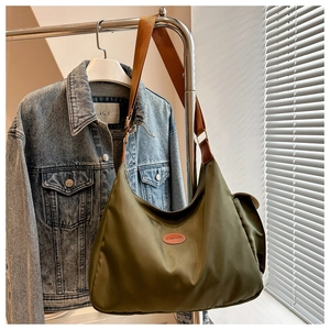 Detail der olivgrünen Halbmond-Tasche mit braunem Lederpatch und breitem Schultergurt