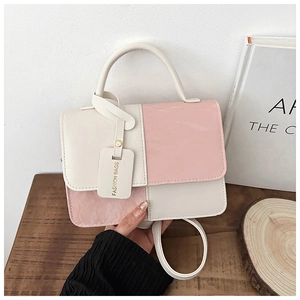 Detail of a pink and cream contrast crossbody bag with a fashion hangtag and texture