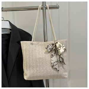 Détail d'un sac cabas en paille tissée avec foulard en soie et anse en corde
