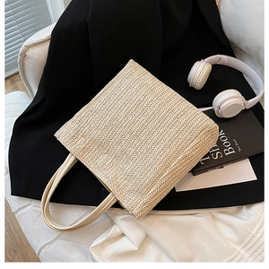 Dettaglio borsa tote in paglia intrecciata con manici crema e trama artigianale