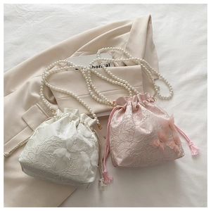 Detail of floral embroidery and 3D butterfly applique on a mini pearl chain bucket bag