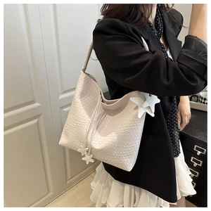 Détail du sac cabas tissé crème avec breloques étoiles et texture de bandoulière raffinée