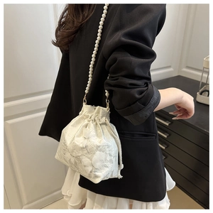 Detailed shot of white lace bucket bag with 3D floral embroidery and pearl chain strap