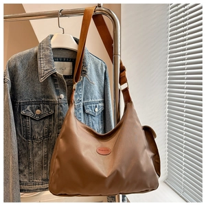 Detail einer braunen Nylon-Umhängetasche mit Fashion-Patch und breitem Stoffschultergurt