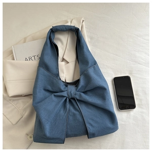 Gros plan détaillé du grand nœud sur le sac cabas en denim bleu avec texture souple