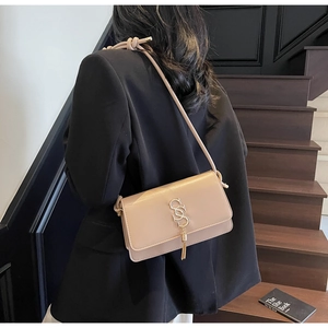 Detail of beige PU leather flap bag with gold SS logo and knotted rope strap