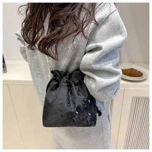 Close-up of black lace bucket bag with 3D butterfly decor and pearl chain strap