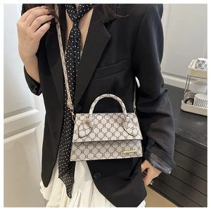 Détail du sac bandoulière vintage avec logo doré sur rabat blanc crème