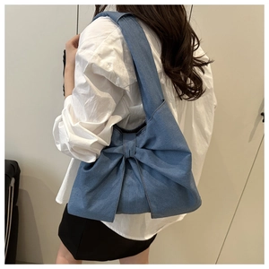 Détail du sac cabas en denim bleu clair avec un grand nœud et une large bandoulière