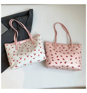 Vue à plat de grands sacs fourre-tout à imprimés cerises et fraises sur fond gris