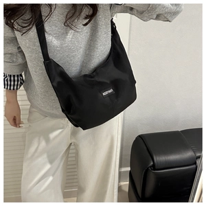 Détail d'un sac bandoulière en nylon noir de forme croissant avec sangle réglable