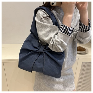 Vue détaillée d'un sac à épaule en jean bleu foncé avec un grand nœud décoratif