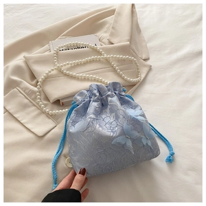 Detail of light blue lace bucket bag featuring 3D butterfly appliques and pearl chain