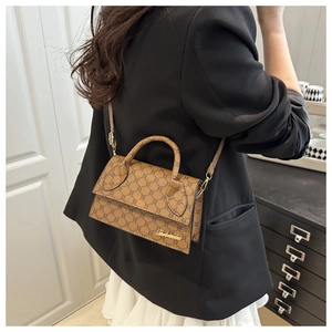 Petit sac carré marron avec motif monogramme et bandoulière porté par un mannequin femme