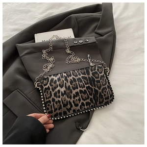 Détail d'un sac bandoulière léopard avec clous argentés et chaîne en métal