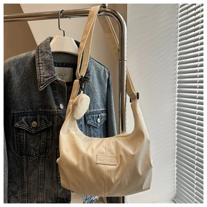 Détail du sac hobo en nylon crème avec bandoulière large et petite pochette assortie