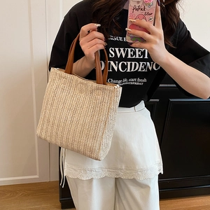 Minimalist straw tote bag with brown leather handles in a stylish woven texture