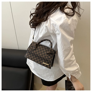 Détail d'un sac porté épaule marron vintage avec motif monogramme et logo doré chic