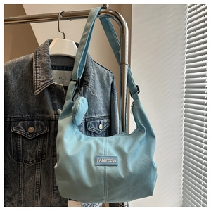 Détail d'un sac à bandoulière bleu clair à texture velours et son petit porte-monnaie