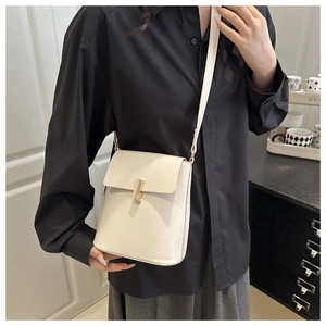 Détail d'un sac bandoulière vertical crème avec boucle dorée et bandoulière en cuir