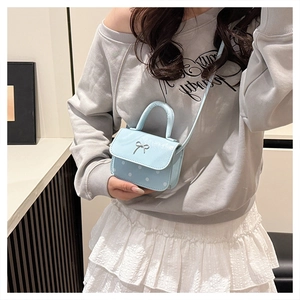 Détail du mini sac bleu clair à pois blancs avec un petit nœud argenté