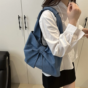 Grand sac cabas en denim avec un nœud papillon géant porté par un mannequin femme