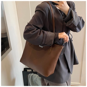 Détail du sac cabas en cuir grainé marron foncé porté avec un blazer gris