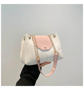 Detail der farblich abgesetzten Damentasche mit goldener Kette und rosa Schultergurt