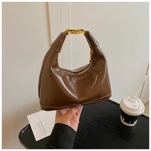 Détail du sac demi-lune marron avec boucle en métal doré et texture en cuir poli