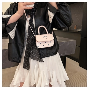 Gros plan du mini sac à pois rose avec détail de nœud papillon en métal argenté
